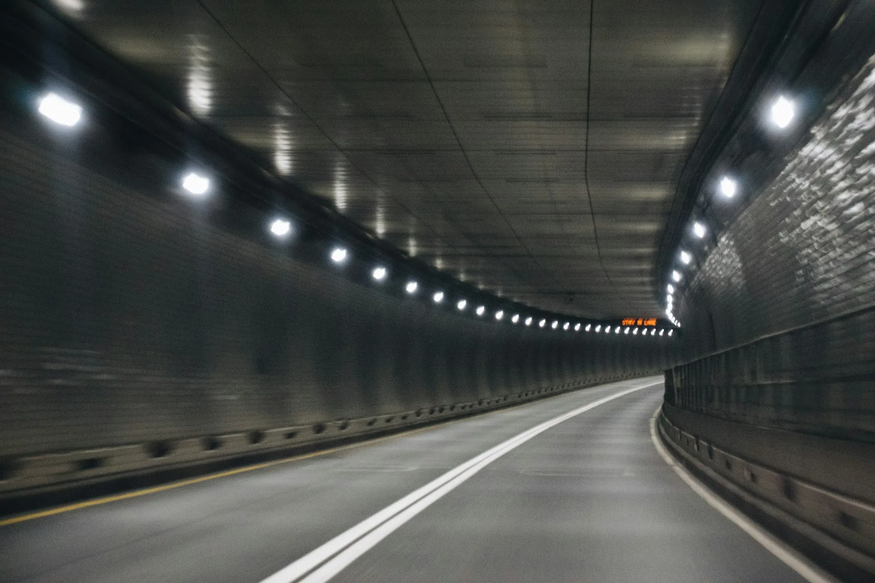 Interior de un túnel de carretera con iluminación continua y panel de mensaje variable